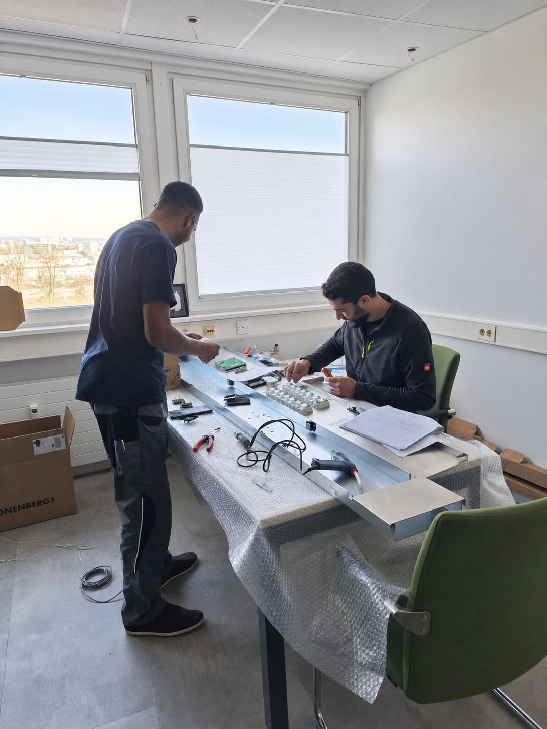 Zwei AMS Techniker bereiten Aufzugskomponenten sorgfältig für ein Projekt vor
